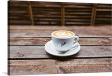  Create a warm and welcoming environment with this lovely picture of a delicious latte. This fine cup of coffee has beautiful latte art and is placed upon a wooden table. This piece would look great in the kitchen, in a cafe, or anywhere in the home.