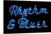 “Neon Rhythm & Blues Sign.The Alabama Music Hall of Fame” by Carol M. Highsmith is a captivating digital artwork that encapsulates the soulful essence and rhythmic heartbeat of iconic music genres. The artwork features bright blue neon lettering spelling out “Rhythm & Blues” against a dark background, evoking a sense of nostalgia and timeless elegance. The neon lettering emits a soft glow that illuminates their surroundings, casting mesmerizing reflections that dance on the sleek surface beneath. 