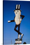 Step into a world where whimsy and nostalgia reign supreme with this exclusive print of the iconic “Mr. Peanut” artwork. This playful piece captures a larger-than-life peanut character, adorned in classic attire, dancing against the backdrop of a clear blue sky. Every detail, from his top hat to his polished shoes, exudes an air of vintage charm that will transport you back to simpler times. 