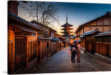  “Women Exploring a Japanese Village in Yukata” invites you into a world where tradition and elegance intertwine seamlessly. This captivating print captures two women adorned in graceful yukatas as they wander through an ancient Japanese village. The warm glow of the setting sun illuminates their path, casting gentle light on wooden structures and intricate details. 