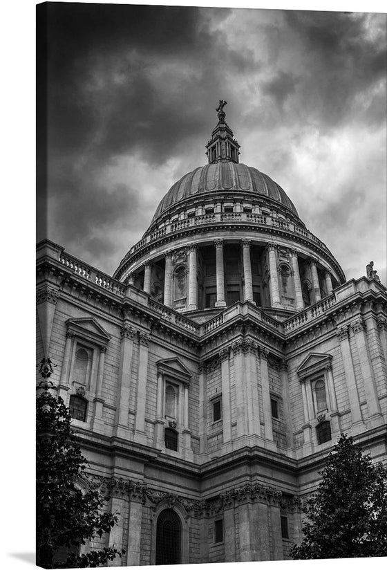 Adorn your space with the mesmerizing allure of this exquisite print, capturing the iconic architecture of a grand building. The image, steeped in monochromatic elegance, showcases the intricate details of the edifice’s majestic dome and ornate facade. A dramatic sky, painted with swirling clouds, casts an enigmatic aura that beckons viewers into a world where classic splendor meets atmospheric mystique. 