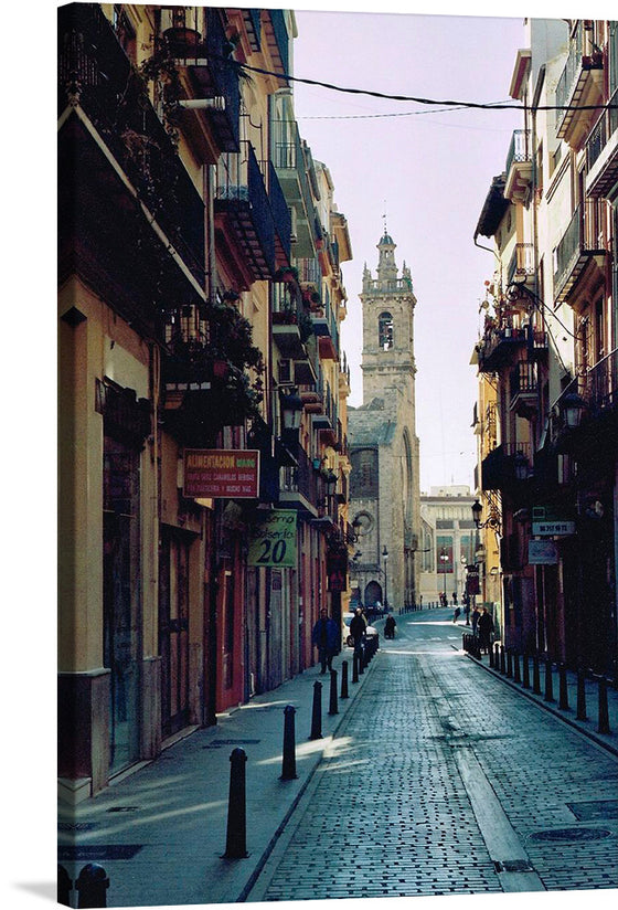 “Russafa Streets, Valencia, Spain” is a stunning artwork that captures the essence of Valencia’s charming streets. The warm hues of the buildings and the intricate architectural designs are captured with stunning clarity. The cobblestone path leads your gaze towards the majestic bell tower that stands as a testament to Valencia’s rich history. 