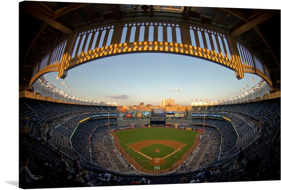 “A View of Yankee Stadium” at sunset is a symphony of patriotism and sporting grandeur. As the sun dips below the horizon, it bathes the iconic stadium in a warm, golden glow. The meticulously manicured field awaits the clash of titans, while the stands hum with anticipation. But it’s the celestial performance above that steals the show—the F-16C Fighting Falcons streak across the sky, their contrails echoing the fervor of the National Anthem. 