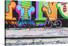  “Bike in Front of Graffiti Wall” invites you to pedal into the vibrant urban jungle. In this captivating artwork, two bicycles casually lean against a wall adorned with bold and colorful graffiti. The structured formality of the bikes contrasts with the wild spirit of street art, creating a dynamic tension. 