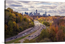  Immerse yourself in the serene beauty of autumn with this exquisite print. The artwork captures a bustling highway, a testament to human ingenuity, nestled amidst nature’s splendor. The golden hues of fall foliage create a stunning contrast against the modern cityscape in the distance, offering a harmonious blend of natural and urban elements. 
