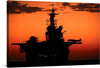 Immerse yourself in the captivating allure of this stunning print, capturing a majestic aircraft carrier silhouetted against the warm hues of a setting sun. Every intricate detail, from the towering command center to the poised aircraft ready for flight, is rendered with exquisite clarity. 