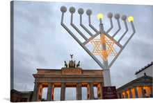  “Hanukkah, Brandenburg Gate” by Olga Ernst is a captivating and unique piece that seamlessly blends tradition and modernity. In this exquisite print, witness the iconic Brandenburg Gate bathed in the soft glow of an oversized menorah, symbolizing the enduring spirit of Hanukkah amidst Berlin’s historic architecture. 