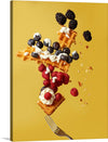 The artwork is of a waffle with raspberries, blueberries, blackberries, and whipped cream. The waffle is in mid-air, and the berries and whipped cream are falling around it. The background is yellow, and there is a fork at the bottom of the image.