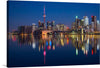 This captivating print captures the tranquil beauty of Toronto, Canada at twilight. The skyline, punctuated by an iconic tower bathed in radiant red light, reflects in the serene waters below, creating a mesmerizing mirror image. As dusk settles, the city’s lights flicker to life, casting vibrant reflections that dance across the water’s surface. 