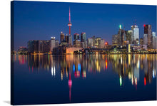  This captivating print captures the tranquil beauty of Toronto, Canada at twilight. The skyline, punctuated by an iconic tower bathed in radiant red light, reflects in the serene waters below, creating a mesmerizing mirror image. As dusk settles, the city’s lights flicker to life, casting vibrant reflections that dance across the water’s surface. 