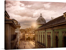  This photograph captures the quaint charm of a Galician town square. The cobblestone streets glisten under the golden light of the setting sun, casting long shadows from the traditional stone buildings. The sky is cloudy and people walk on the cobblestone streets below.