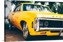  This print features a bright yellow vintage car with a sleek design. The car is parked on a street with trees in the background. The photo has a nostalgic feel, making it a perfect addition to any car enthusiast’s collection. The photograph of the car is captured in a way that makes it look like it’s ready to hit the road. The bright yellow color of the car is eye-catching and adds a pop of color to any room. 