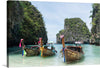 Immerse yourself in the serene beauty of this exquisite print capturing the tranquil waters of a hidden paradise. Three traditional wooden boats, adorned with vibrant ribbons, rest gently on the crystal-clear waters, offering a glimpse into a world where nature and tradition harmoniously coexist. Towering limestone cliffs, veiled in lush greenery, stand as silent sentinels guarding this secluded haven. 