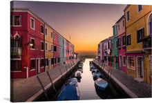  “Sunset in Burano” is a captivating print that transports viewers to the enchanting island of Burano, renowned for its vibrant and whimsical architecture. As the sun gracefully descends, it bathes the canal in warm hues, casting a mesmerizing glow upon the colorful facades of the buildings. Each detail is meticulously captured: the tranquil waters mirror the sky’s brilliance, while boats rest gently along the edges. 