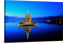  This captivating print captures a moment of serene beauty and festive cheer, where a brilliantly lit Christmas tree stands majestically in the middle of tranquil waters under the enchanting twilight sky. The glittering lights of the tree dance and shimmer, casting a mesmerizing reflection upon the calm waters, creating a harmonious blend of nature’s splendor and holiday illumination. 