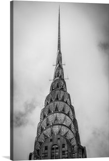  “Black and White Photo of the Top of the Chrysler Building in New York City” captures the essence of urban elegance. Against a backdrop of clouds, the iconic spire of the Chrysler Building pierces the sky, its Art Deco design standing as a testament to human ingenuity. The monochromatic palette emphasizes the building’s intricate details—the stainless steel cladding, the geometric patterns, and the majestic pinnacle.