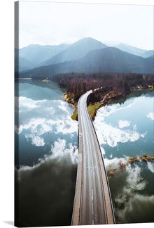  “Sylvenstein Dam, Germany” invites you to a harmonious blend of nature and engineering. This captivating print captures the majestic Sylvenstein Dam stretching across tranquil waters, nestled amidst lush greenery and framed by majestic mountains. The reflection of clouds on the water’s surface adds an ethereal touch, making this artwork a symphony of motion and stillness. 