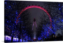  This print, titled “Millennium Wheel in South Bank, London”, is a reproduction of an original artwork that captures a mesmerizing scene of the iconic Ferris wheel illuminated against the tranquil night sky. The radiant glow of red and blue lights casts an ethereal ambiance, weaving through the silhouetted trees and reflecting a dance of colors that brings life to the serene darkness. 