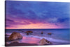 Immerse yourself in the serene beauty of this exquisite print, capturing a tranquil seaside at dusk. The harmonious dance of the vibrant hues of sunset, with purples, pinks, and blues painting the sky, creates a mesmerizing backdrop. The gentle waves kiss the sandy shore where majestic rocks stand as silent witnesses to nature’s awe-inspiring spectacle. 