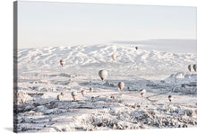  Elevate your space with this mesmerizing print capturing a serene and magical moment where hot air balloons gracefully float above a pristine, snow-covered landscape. The gentle hues of dawn kiss the earth, illuminating the intricate patterns carved by nature into the rolling hills and valleys. Each balloon, adorned with unique designs, adds a splash of color to the tranquil white expanse below. 