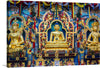 Immerse yourself in the intricate beauty and spiritual serenity encapsulated in this exquisite print, “Namdroling Monastery Golden Temple”. The artwork features three golden statues adorned with elaborate decorations, set against a richly decorated backdrop of vibrant colors and intricate designs. The small figurines surrounding the main statues add to the complexity of the artwork, inviting viewers into a world of peaceful reflection and cultural richness. 