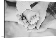  A captivating black and white photograph portraying the profound connection between a family's love, symbolized by the tender grip of their intertwined hands. This touching image is perfect for those seeking a timeless and heartfelt print to adorn their walls.