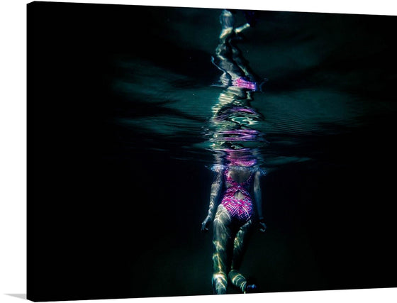 Dive into the enigmatic allure of this mesmerizing artwork. This print captures the ethereal dance of light and water, with a figure adorned in a vibrant swimsuit suspended in the serene embrace of the deep, dark waters. The surface above mirrors their form, creating a symphony of reflections that dance and shimmer with every gentle wave. 