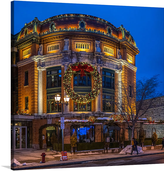  “Place D’Youville, Quebec City, Canada 4.” This artwork captures the enchanting atmosphere of a snowy Canadian evening, where classic elegance meets festive cheer. The ornate building at Place D’Youville is illuminated by soft lighting, highlighting its intricate architectural details. A large Christmas wreath adorned with lights hangs prominently on the front of the building, adding to the festive ambiance. 