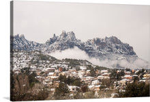  This exquisite print invites you into a serene winter scene of a village nestled at the foot of majestic, snow-capped mountains. The delicate dance of mist weaving through the rocky peaks evokes a sense of ethereal tranquility. The cozy homes, each unique in design and color, are blanketed in snow, adding to the charm of this picturesque landscape. 