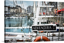  “Yachts Docking at Marina in France” invites you into a world of nautical elegance. This captivating print captures the essence of luxury and tranquility. The majestic yacht named “ADVENTURA” stands tall, its intricate rigging and polished hull reflecting opulence. As it docks gracefully, historic buildings line the marina, their classic architecture providing a timeless backdrop. 