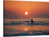 Immerse yourself in the serene beauty of this exquisite print, capturing a tranquil moment of solitude amidst the gentle waves. As the sun dips below the horizon, painting the sky with warm hues of orange and pink, a lone figure is silhouetted against its radiant glow. Birds dance in the fading light, their silhouettes adding a touch of life to this peaceful scene. 