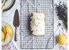 "Freshly baked lemon cake with icing and lavender flowers"