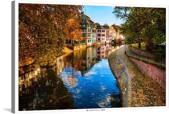 Immerse yourself in the enchanting atmosphere of “Little Paris Strasburg France” with this captivating print. The artwork transports you to a serene morning in Strasbourg, where the city’s iconic architecture is mirrored gracefully on the tranquil waters of the canal. Framed by autumn leaves painted with strokes of gold and amber, this picturesque scene invites a sense of calm and reflection. 