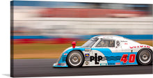  Capture the thrill of the race with this dynamic print featuring a sleek racing car, number 40, in action. The artwork encapsulates the essence of speed and competition, as blurred lines in the background vividly portray the car’s rapid motion. Adorned with an array of sponsor logos and a striking blue and white color scheme, this piece is a must-have for any motorsport enthusiast looking to bring a touch of adrenaline to their living space. 