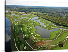  This captivating print offers an aerial view of a meticulously designed golf course, nestled amidst the embrace of nature. The lush green fairways, intricately woven between pristine lakes and bordered by forests, create a visual symphony of color and texture. Each curve and contour is a testament to the harmonious blend of man-made artistry and natural splendor. 