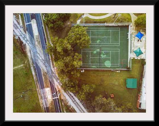 "Roadway and Train Tracks Next to a Tennis Court"