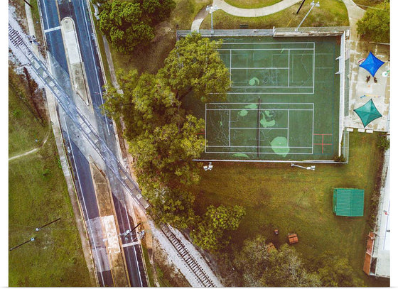 "Roadway and Train Tracks Next to a Tennis Court"