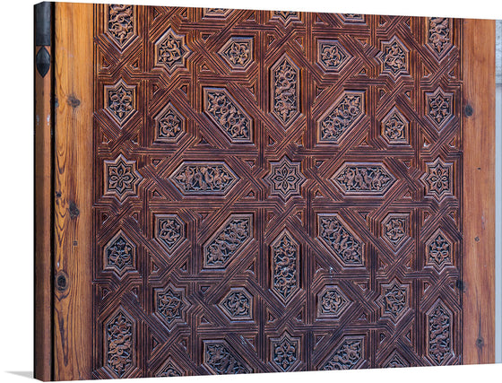 This intricate and beautiful wooden door detail from the Abenceraje Room in the Alhambra Palace in Granada, Spain is a stunning example of Moorish architecture and craftsmanship. The door is covered in intricate carvings of geometric patterns, stylized flowers, and Arabic inscriptions.