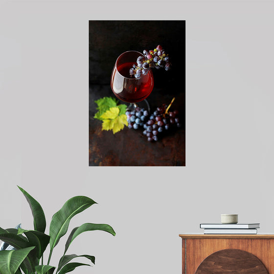 "Macro view of a wine glass containing alcoholic wine with a bunch of grapes."