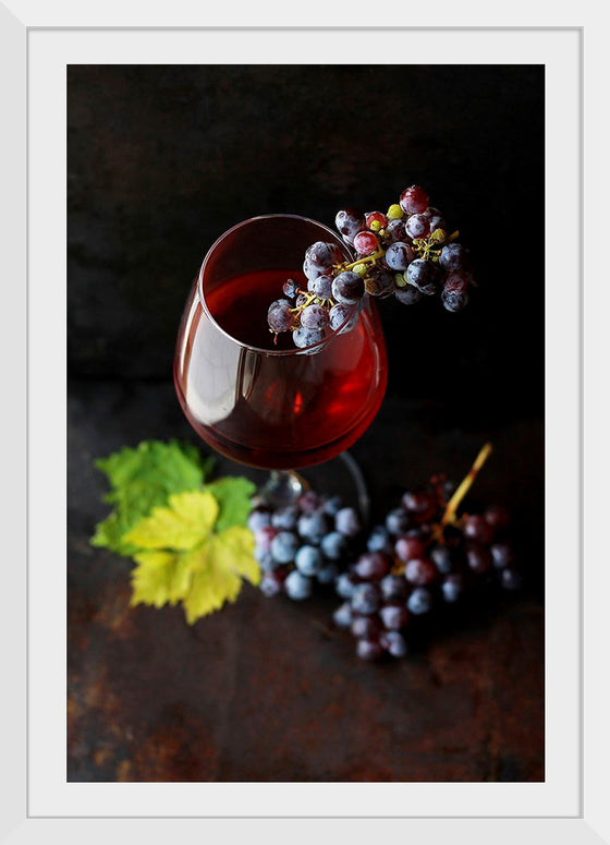 "Macro view of a wine glass containing alcoholic wine with a bunch of grapes."