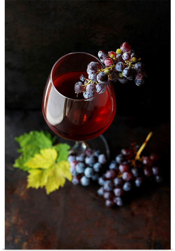 "Macro view of a wine glass containing alcoholic wine with a bunch of grapes."