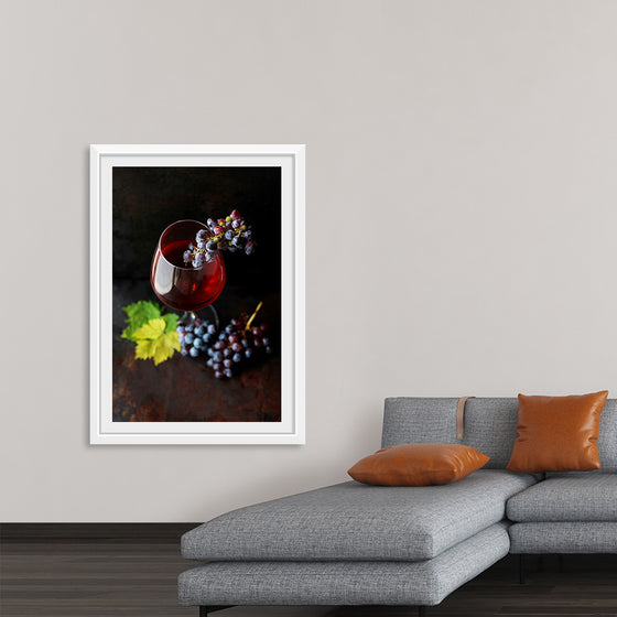 "Macro view of a wine glass containing alcoholic wine with a bunch of grapes."