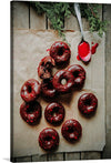 This print is a beautiful and mouth-watering image of chocolate doughnuts with red drizzle. The doughnuts are arranged in a scattered manner with one doughnut having a bite taken out of it. The red drizzle is in a zigzag pattern on the doughnuts. 