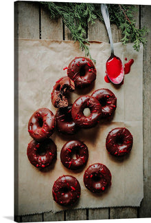  This print is a beautiful and mouth-watering image of chocolate doughnuts with red drizzle. The doughnuts are arranged in a scattered manner with one doughnut having a bite taken out of it. The red drizzle is in a zigzag pattern on the doughnuts. 
