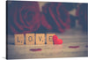 Immerse yourself in the tender embrace of “Whispers of Affection,” a captivating print that encapsulates the essence of love. Wooden scrabble tiles spell out “LOVE” against a backdrop adorned with soft-focus roses, their rich hues painting a scene of warmth and romance. A small, vibrant red heart nestles beside the letters, embodying the unspoken emotions that words alone cannot convey. 