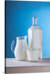Introducing our latest art print, a serene and elegant portrayal of purity and nourishment. This artwork captures the simplistic beauty of a bottle, a jug, and a glass filled with fresh milk against the backdrop of an enchanting azure blue wall. The harmonious blend of white and blue evokes feelings of calmness and tranquility. 