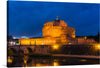 “Castel Sant’Angelo at dusk, Rome, Italy” by Gary Todd is a stunning photograph that captures the essence of Rome. The image showcases the historic castle at dusk, with the warm glow of the lights reflecting off the water. The deep blue sky and the few visible clouds add to the beauty of the photograph. The image is taken from a distance, with the castle and bridge taking up most of the frame.