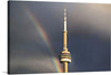 This captivating print captures the iconic tower standing majestically against a dramatic sky, with a radiant rainbow gracing the scene. The contrast between the dark, ominous clouds and the vibrant spectrum of colors from the rainbow creates a visually striking effect. The tower, bathed in natural light, stands as a beacon of architectural splendor.