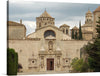 This print captures the grandeur of an ancient architectural masterpiece, possibly a cathedral, standing as a testament to timeless elegance. The intricate carvings and statues that adorn its majestic facade are beautifully detailed, showcasing the artistry of a bygone era. Underneath the overcast sky, the edifice is surrounded by lush greenery, adding a touch of serenity to the scene. 