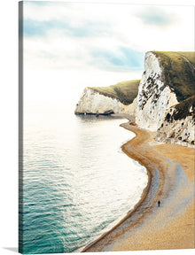  “Walking on Winding Sands” invites you to the edge of a world where land and sea embrace in timeless harmony. These majestic cliffs, like ancient guardians, stand tall against the horizon. Their white faces, etched by eons of wind and waves, exude a quiet strength. Below, a narrow beach curves gently, inviting solitary footsteps. A lone figure walks, a silhouette against the vastness, lost in contemplation.